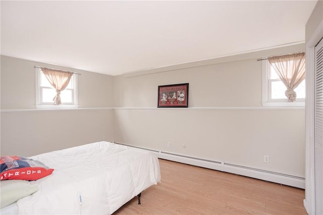 bedroom with light hardwood / wood-style floors and a baseboard radiator