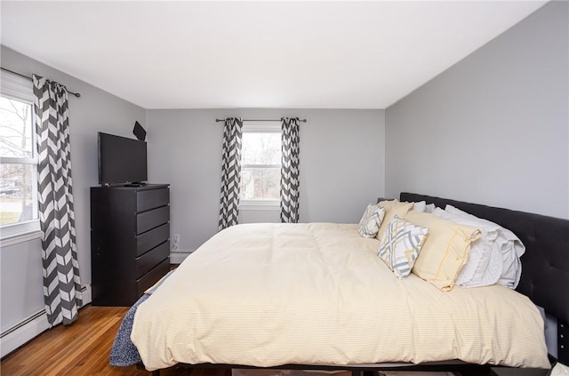 bedroom with hardwood / wood-style flooring and baseboard heating