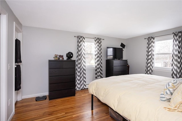 bedroom featuring hardwood / wood-style floors, multiple windows, and a baseboard heating unit