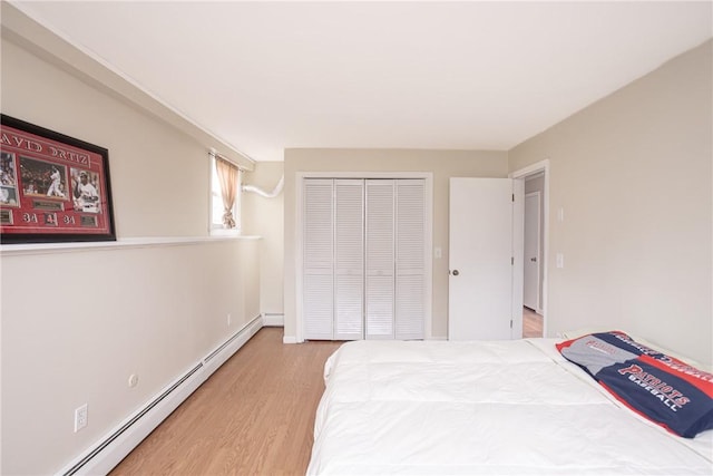 bedroom featuring wood-type flooring, a closet, and a baseboard heating unit