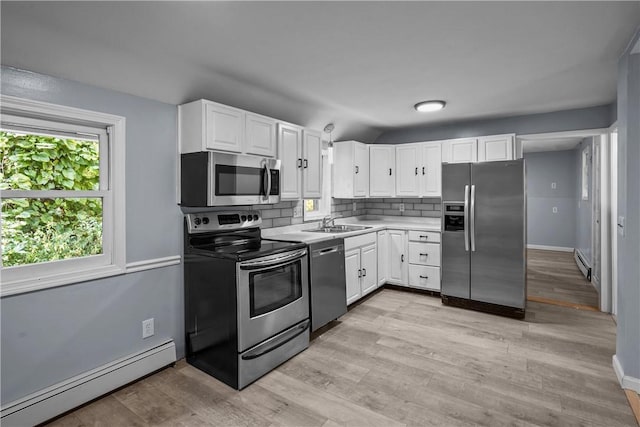 kitchen with tasteful backsplash, white cabinets, stainless steel appliances, and a baseboard heating unit