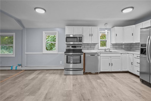 kitchen featuring decorative backsplash, stainless steel appliances, a baseboard heating unit, sink, and white cabinets