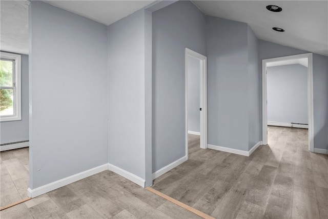 interior space featuring a baseboard radiator, lofted ceiling, and light wood-type flooring