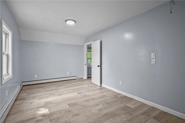 unfurnished room with a baseboard heating unit, a healthy amount of sunlight, and vaulted ceiling