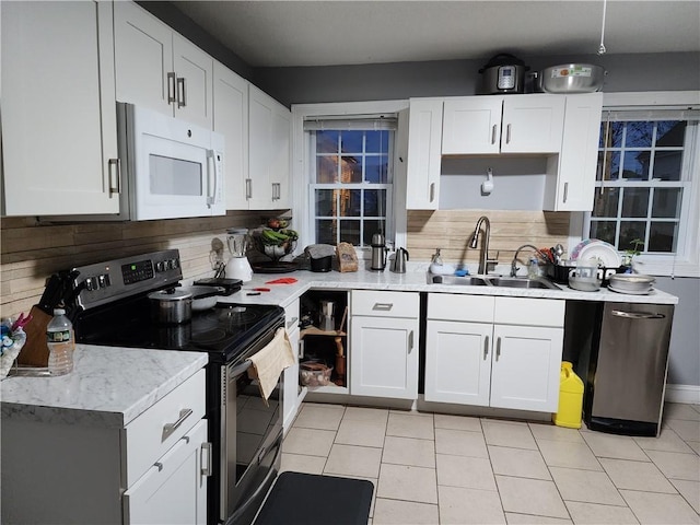 kitchen with appliances with stainless steel finishes, tasteful backsplash, sink, light tile patterned floors, and white cabinets