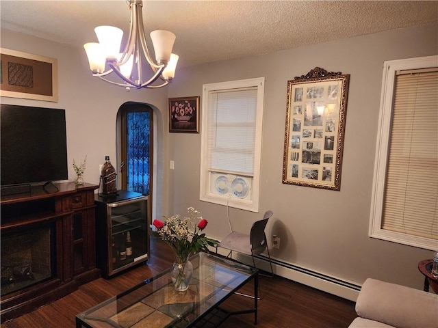 living room featuring wine cooler, dark hardwood / wood-style floors, a textured ceiling, a baseboard radiator, and a notable chandelier