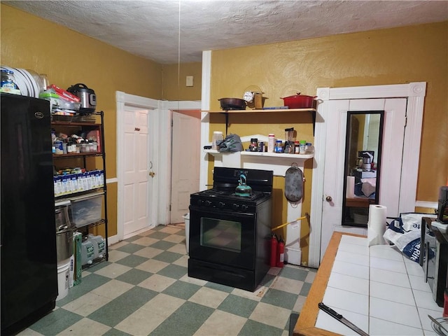 kitchen featuring black gas range and a textured ceiling