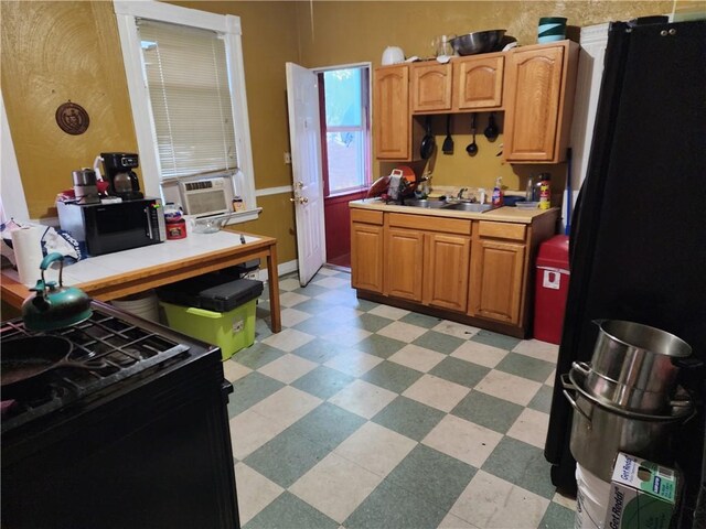 kitchen featuring black fridge, cooling unit, and sink