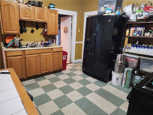 kitchen featuring tile countertops, black refrigerator with ice dispenser, and sink