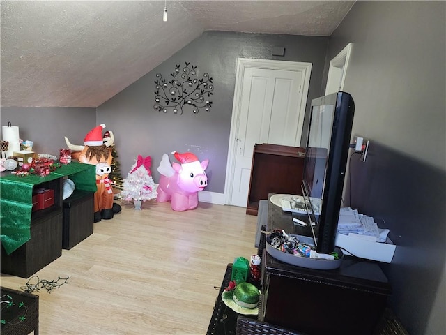 playroom with light hardwood / wood-style flooring, a textured ceiling, and vaulted ceiling