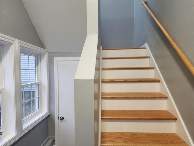 staircase featuring plenty of natural light and vaulted ceiling