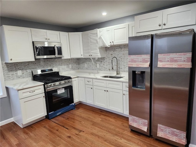 kitchen featuring white cabinets, light wood-type flooring, stainless steel appliances, and sink