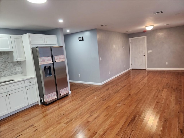 kitchen featuring decorative backsplash, white cabinetry, light hardwood / wood-style floors, and stainless steel refrigerator with ice dispenser