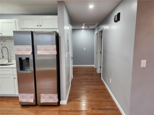 kitchen with decorative backsplash, stainless steel fridge with ice dispenser, sink, and white cabinets