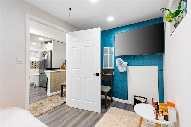 bedroom featuring hardwood / wood-style flooring and stainless steel fridge