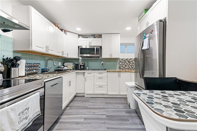 kitchen featuring white cabinetry, sink, appliances with stainless steel finishes, and wall chimney range hood