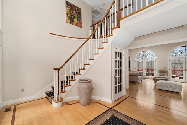 interior space with french doors, a towering ceiling, and hardwood / wood-style flooring