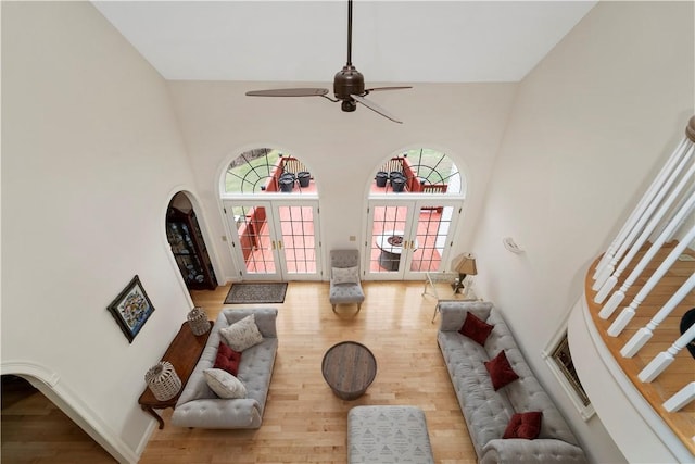 living room with french doors, a towering ceiling, ceiling fan, and wood-type flooring