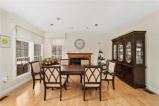 dining room with light wood-type flooring and ornamental molding