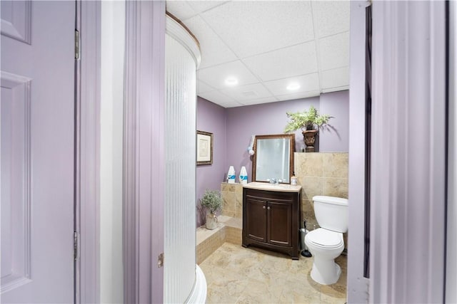 bathroom featuring vanity, toilet, and a paneled ceiling