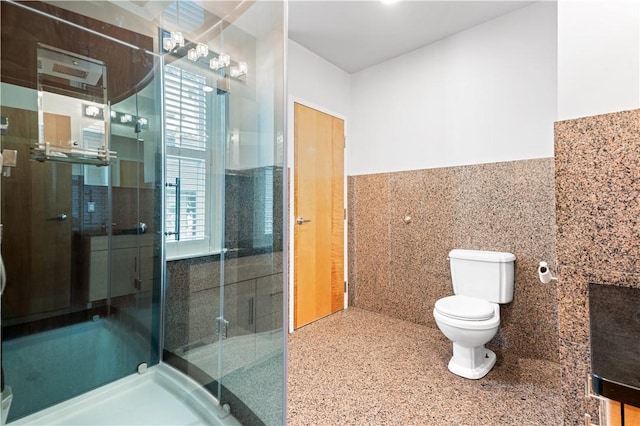 bathroom featuring an enclosed shower, toilet, tile walls, and a healthy amount of sunlight