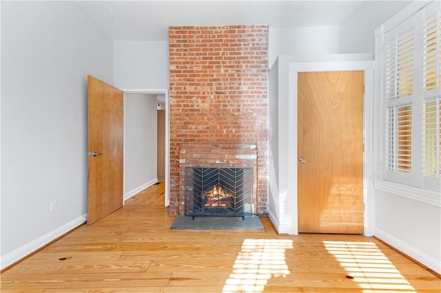 unfurnished living room with hardwood / wood-style floors and a brick fireplace