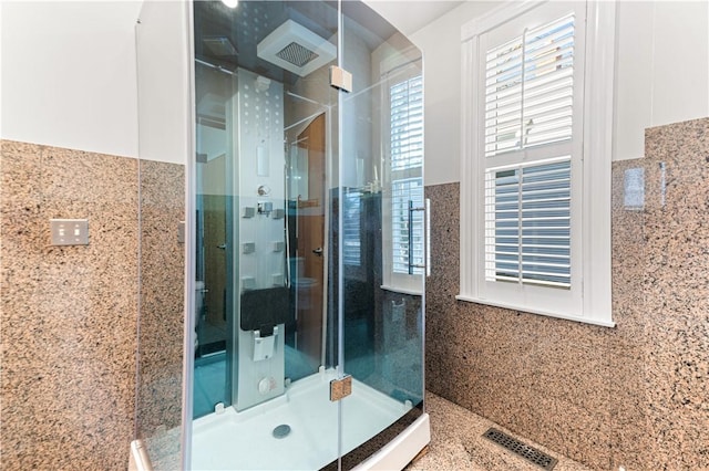 bathroom featuring a shower with shower door and tile walls