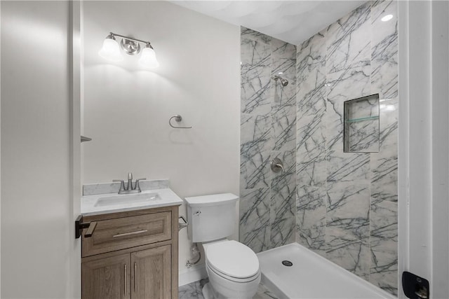 bathroom with vanity, toilet, and tiled shower