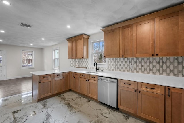 kitchen with kitchen peninsula, backsplash, stainless steel dishwasher, a wealth of natural light, and sink