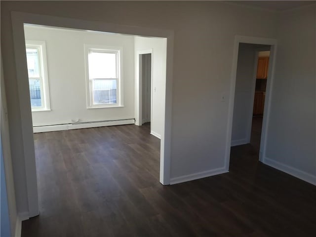 unfurnished room featuring dark wood-type flooring and a baseboard heating unit