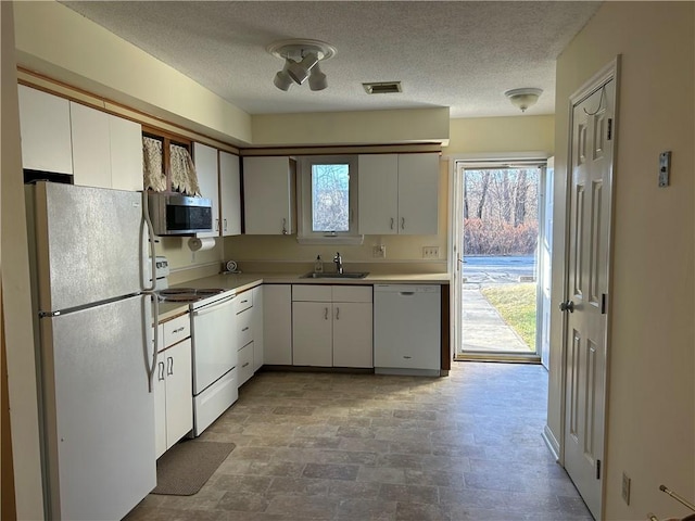 kitchen featuring sink, white appliances, white cabinetry, and a textured ceiling