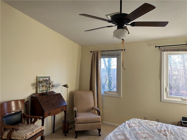 bedroom with ceiling fan, light colored carpet, and a textured ceiling