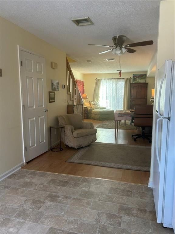 unfurnished living room with a textured ceiling and ceiling fan