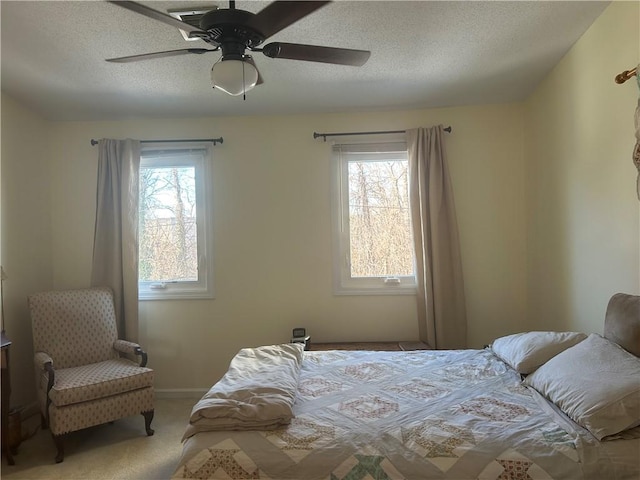 carpeted bedroom featuring multiple windows, a textured ceiling, and ceiling fan