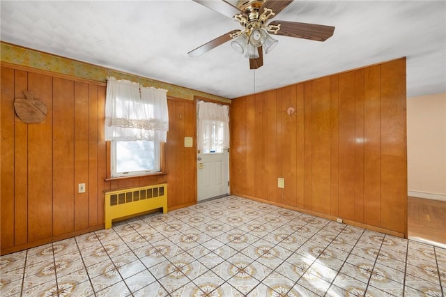 interior space with radiator heating unit, ceiling fan, and wood walls