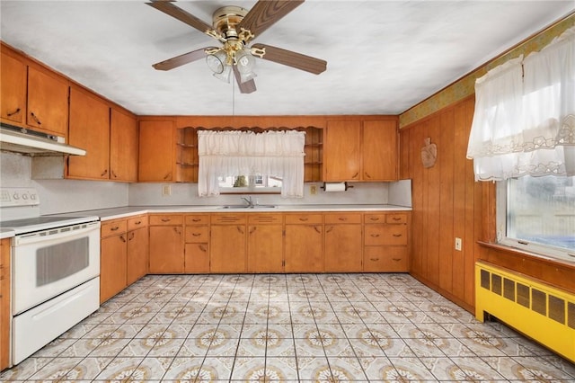 kitchen featuring radiator heating unit, white electric range, a wealth of natural light, and sink