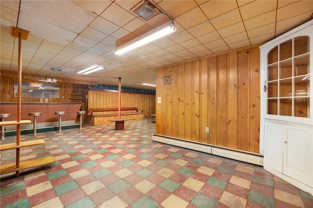 basement featuring a baseboard radiator and wood walls