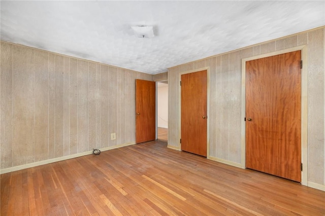 unfurnished bedroom featuring hardwood / wood-style floors and wooden walls