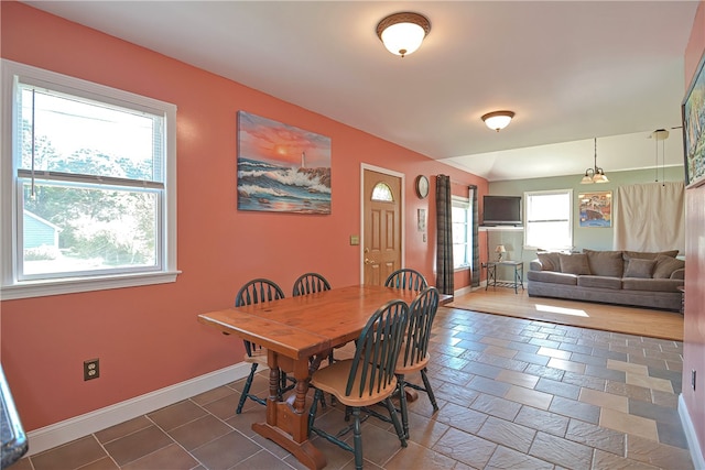 tiled dining room featuring lofted ceiling