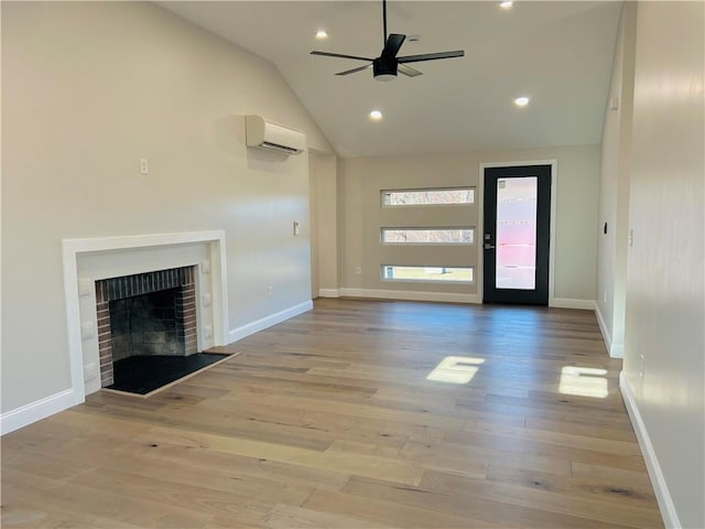 unfurnished living room featuring an AC wall unit, vaulted ceiling, ceiling fan, a fireplace, and light hardwood / wood-style floors