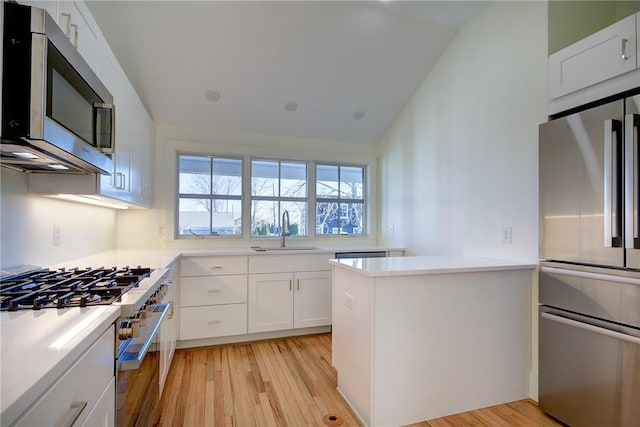 kitchen with sink, stainless steel appliances, white cabinetry, and lofted ceiling