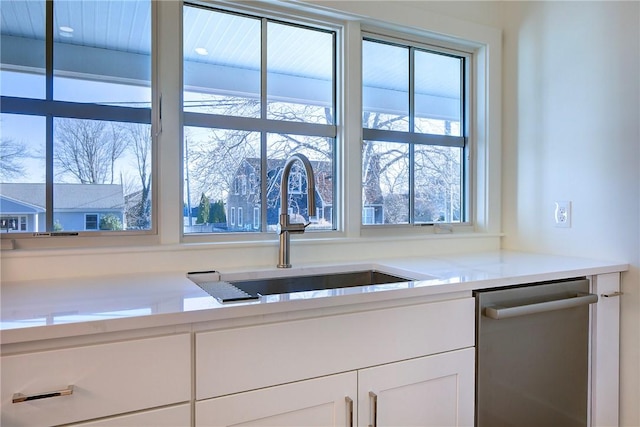 kitchen with sink, white cabinetry, stainless steel dishwasher, and a healthy amount of sunlight