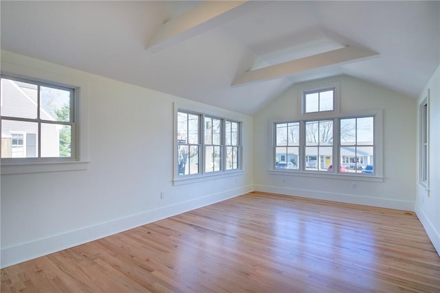 spare room featuring vaulted ceiling with beams and light hardwood / wood-style flooring