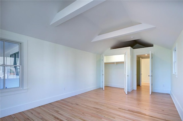 unfurnished bedroom featuring light hardwood / wood-style floors, a closet, and lofted ceiling with beams