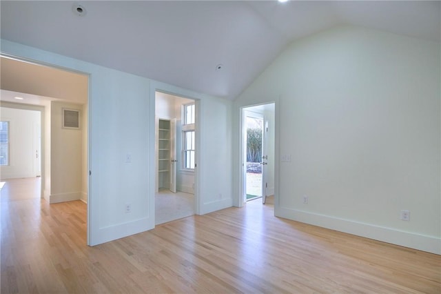 empty room with light hardwood / wood-style floors and vaulted ceiling