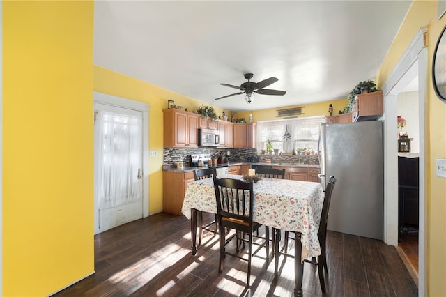 kitchen featuring appliances with stainless steel finishes, tasteful backsplash, ceiling fan, and dark wood-type flooring