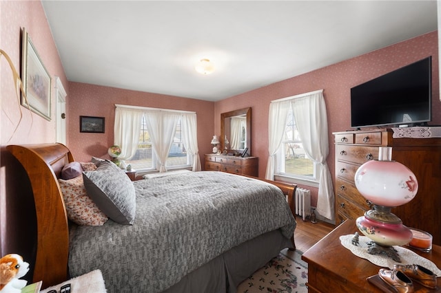 bedroom featuring radiator heating unit and hardwood / wood-style flooring