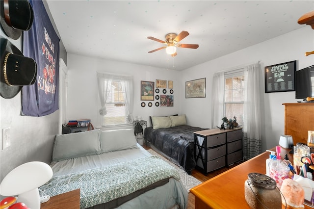 bedroom with ceiling fan, wood-type flooring, and multiple windows