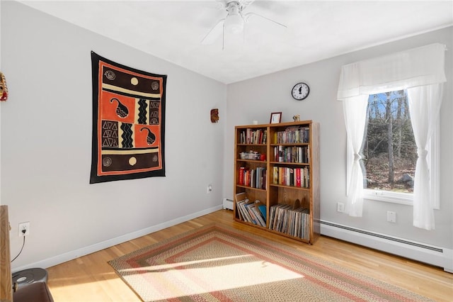 living area featuring hardwood / wood-style flooring, plenty of natural light, ceiling fan, and a baseboard heating unit