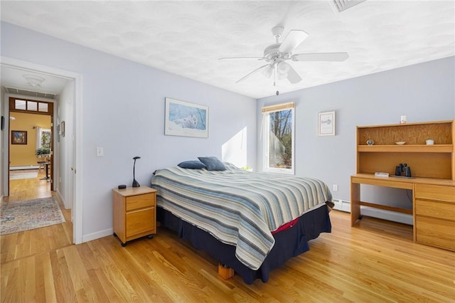 bedroom featuring ceiling fan, light hardwood / wood-style flooring, and a baseboard heating unit